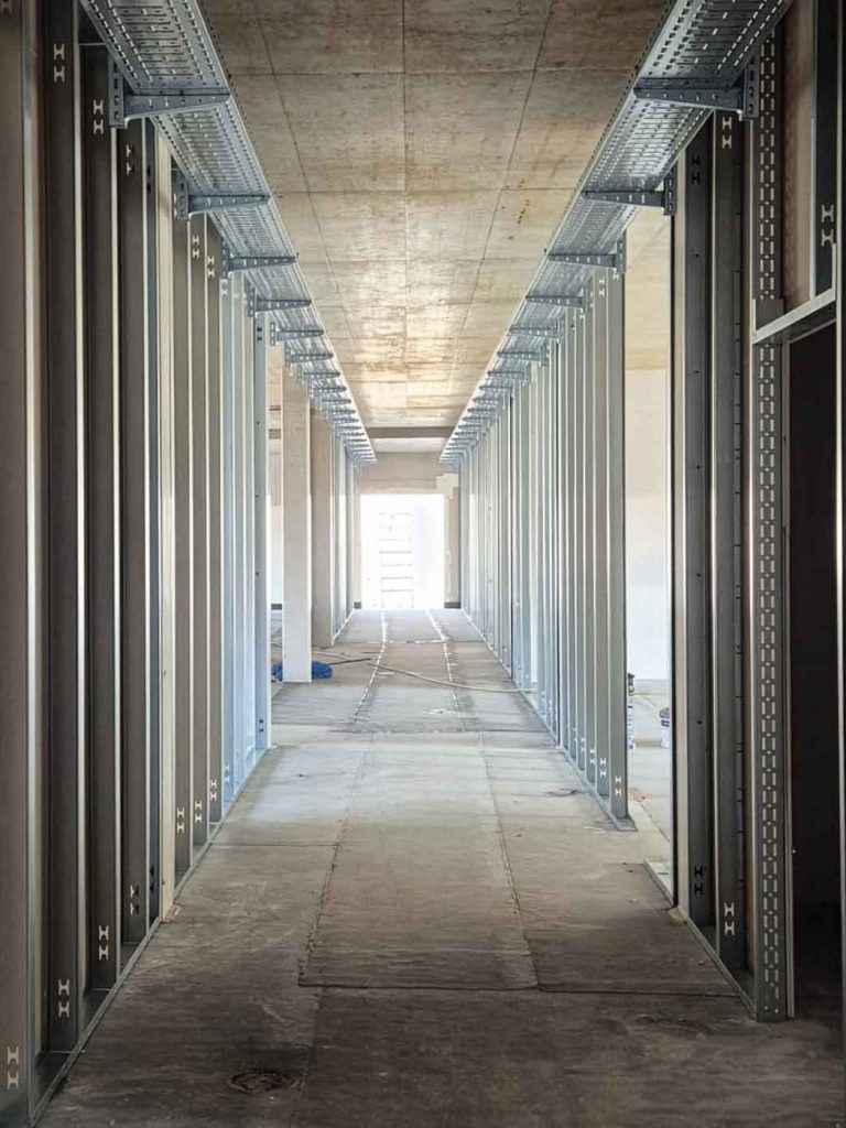Ein langer Gang im Trockenbau, Baustelle mit Schienen und Leisten zur Vorbereitung von Trockenbau Wänden. Ein Projekt von GT Innenausbau in Pitten 